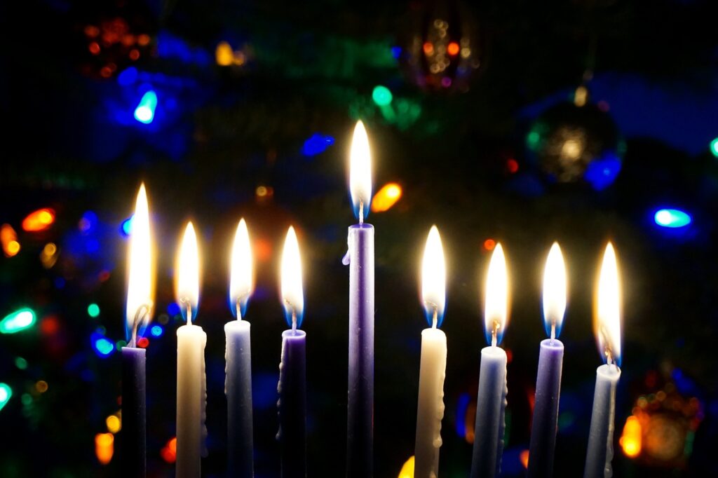 נרות חנוכה דולקים על רקע אורות צבעוניים מטושטשים