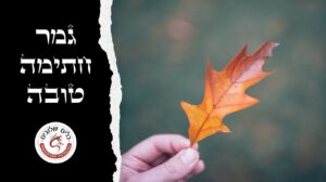 יד אוחזת עלה שלכת כתום על רקע מטושטש, לצד הכיתוב גמר חתימה טובה